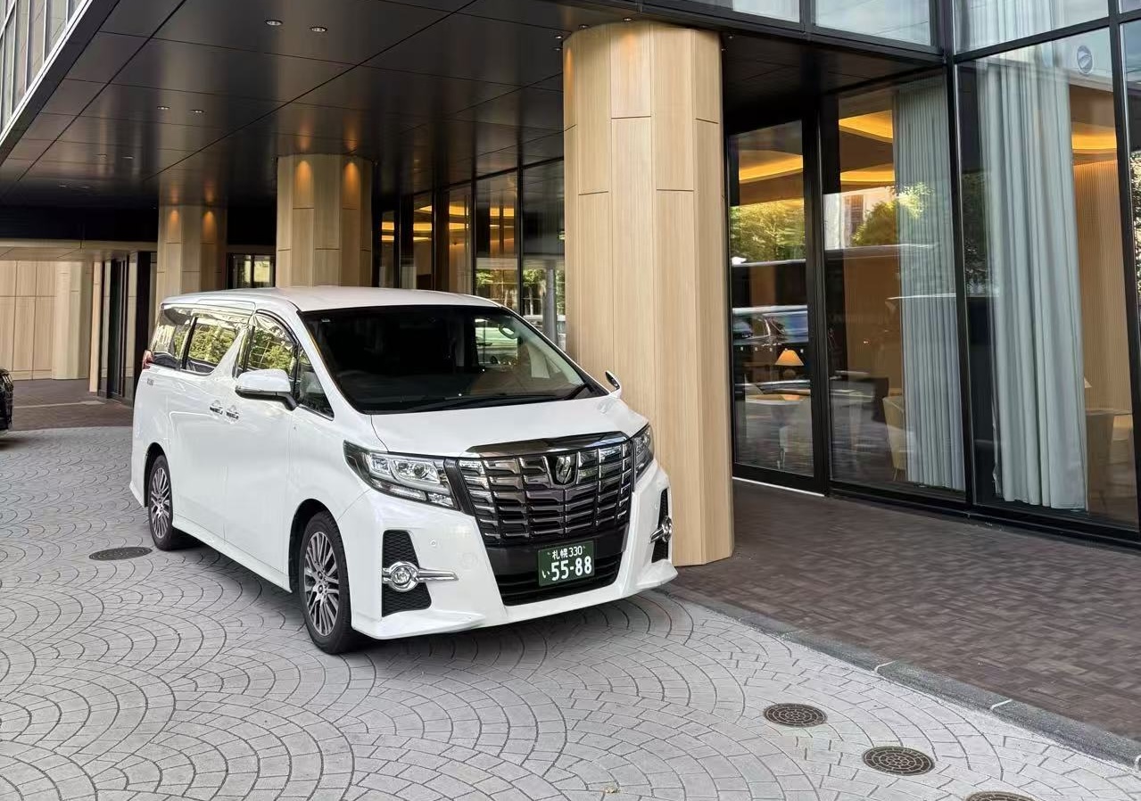 White Toyota Alphard private chauffeur vehicle at a luxury hotel entrance in Sapporo